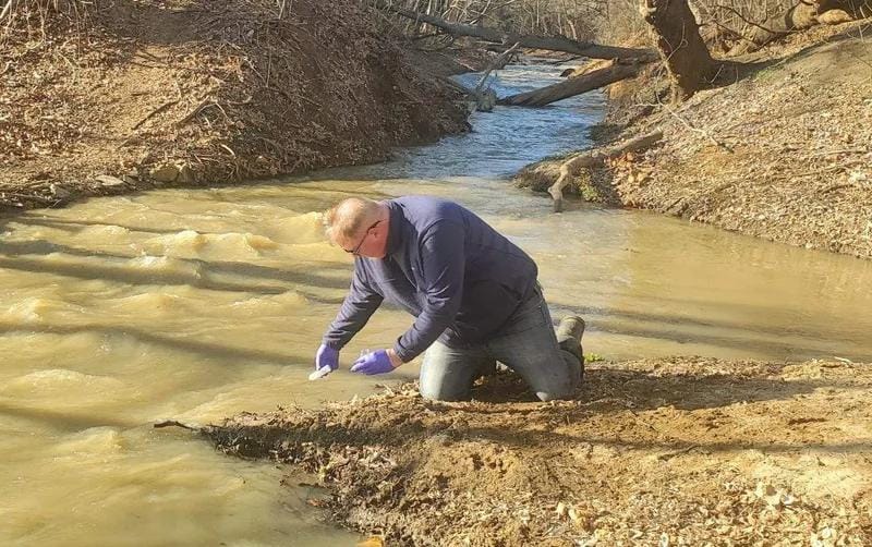 Environmental advocate collecting water samples from sewage spill northwest of D.C