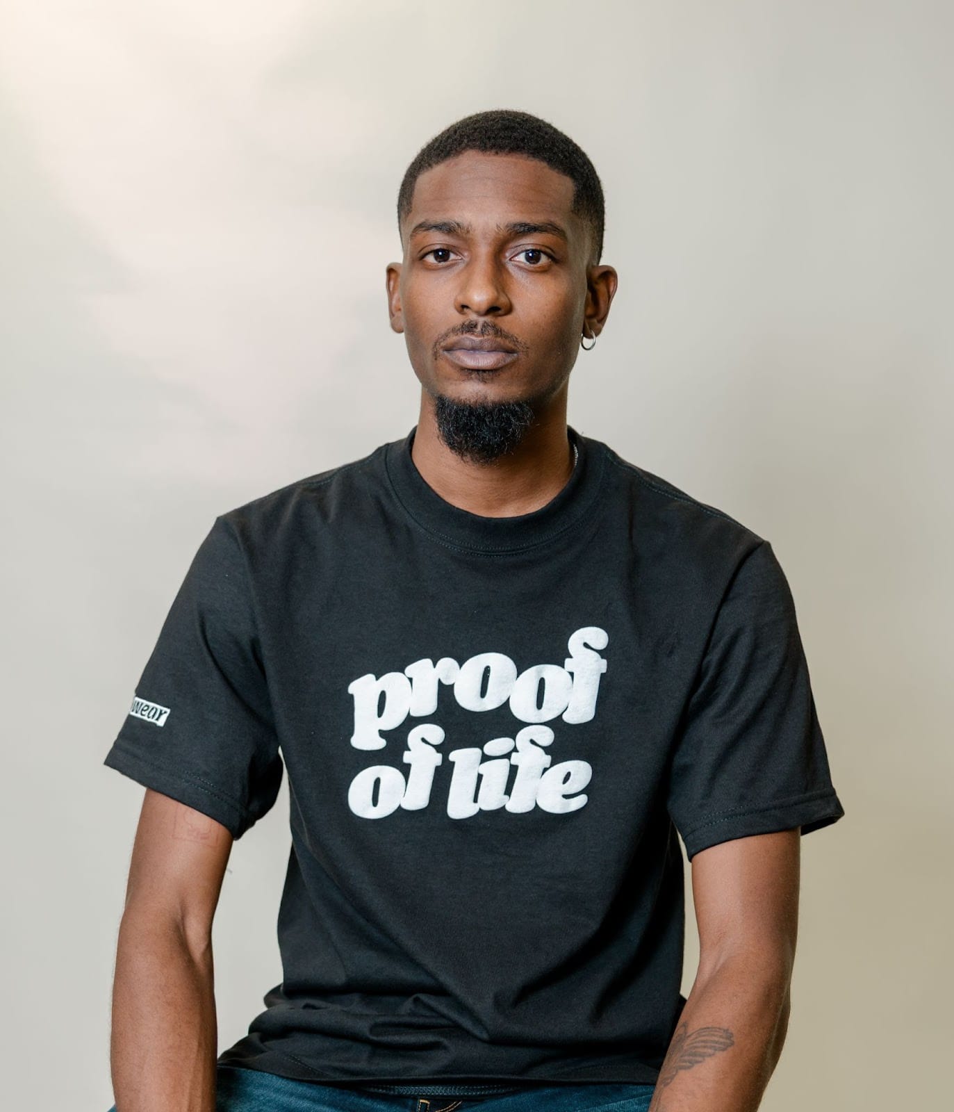 A portrait of Ty Hobson-Powell wearing a shirt that reads "Proof of Life."