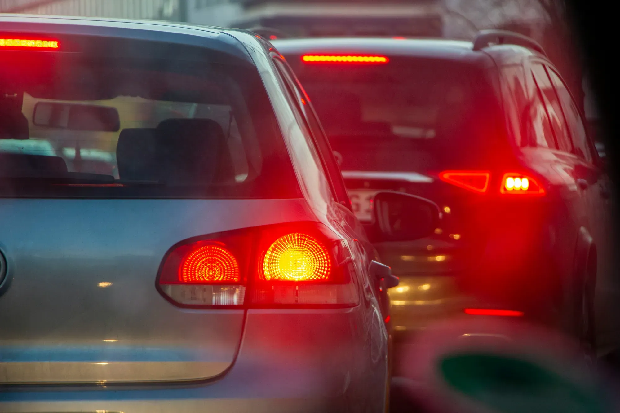 A closeup of two cars sitting in bumper to bumper traffic 