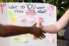 Photo showing two people standing next to a board that reads "What to YOU want from local news?", talking to a man.