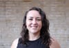 A headshot of Abigail Higgins with a brick wall in the background.