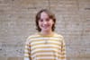 A headshot of featured team member Colleen Grablick, with a brick wall in the background.