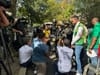 Un grupo de bomberos y rescatistas habla ante un grupo de periodistas que sostienen micrófonos y cámaras.