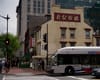 A view of an intersection in D.C.'s Chinatown, with a yellow light and a red walk signal. A metrobus is visible in the frame, and businesses with Chinese lettering are visible in the backgrou