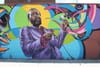 Mural of Marvin Gaye, a Black singer, wearing a purple suit in front of a color, musical background. 