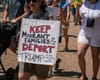 Someone in a protest holds a sign that says Let's Keep Migrant Families & Deport Trum