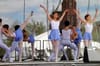 Ballet dancers in white and purple costumes perform on an outdoor stage.