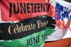 A large red, black, and green flag that says Juneteenth Celebrate Freedom June 19