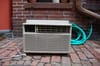 A window AC unit sitting on brick.