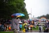 People stand on the National Mall near the Lincoln Memorial with umbrellas and rain gear.