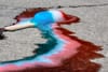 A red, white, and blue popsicle melting on the ground.
