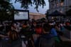 A gathering at dusk before a screen.
