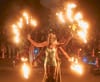 Two dancers hold spokes with flames on the end with a large crowd behind them at the Dupont Circle Fountain.
