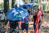 A person walking with a blue umbrella that reads We Are All DC, next to a person with a DC flag.