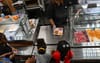 A school lunch worker passes a plate of food to childre standing in line at a school cafeteria