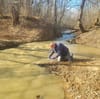 Environmental advocate collecting water samples from sewage spill northwest of D.C