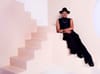 A photograph of a person dressed in all black sitting on a pink staircase.