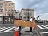 Alan and a friend carry his sign from the median where he hands out water.