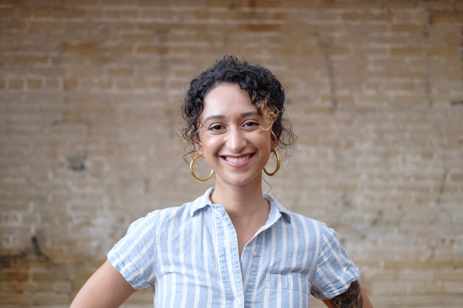 A photo of Natalie standing outside in front of a brick wall.