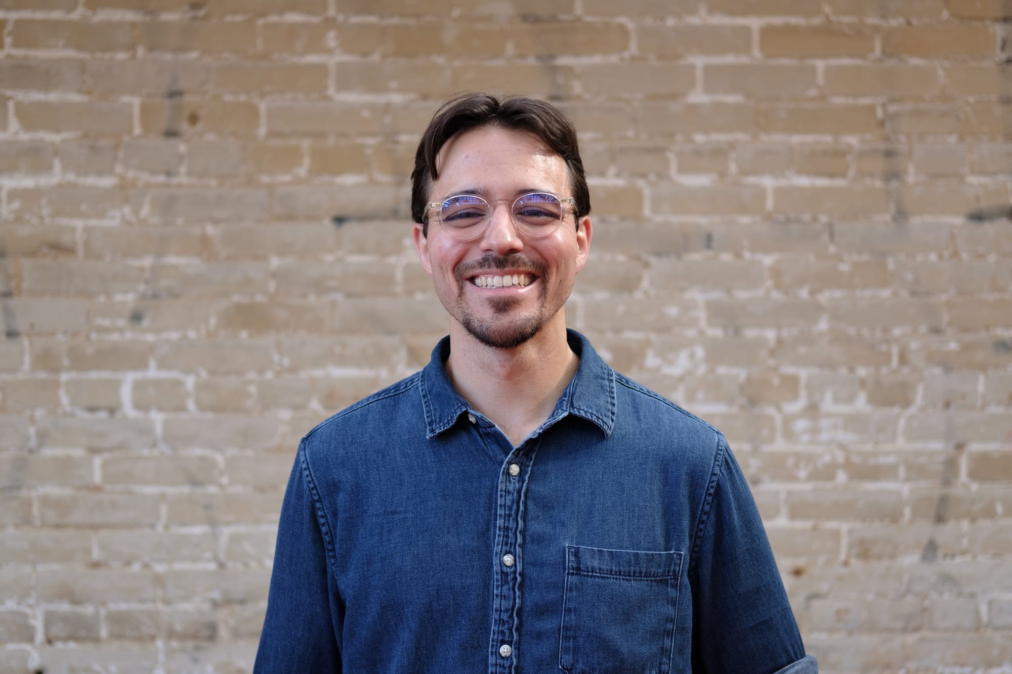 A photo of Eric Falquero outside, standing in front of a brick wall.