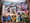 Photo of a colorful mural on a building wall. It depicts multiple groups of people in various neighborhood scenes. 