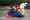 Two people draped in an LGBTQ flag/blanket along a water feature on the National Mall. 