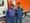 Photo of two men in city employee uniforms standing in front of a white and orange Department of Public Works truck