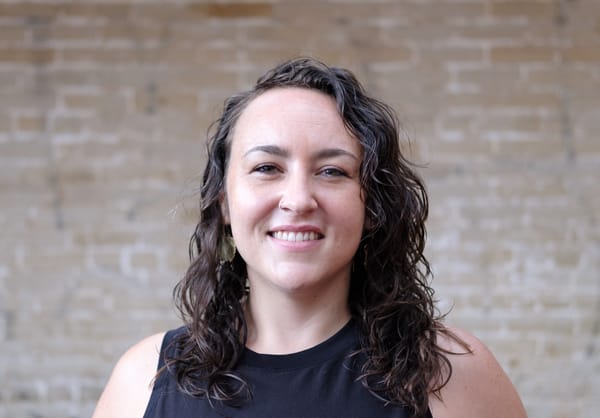 A headshot of Abigail Higgins with a brick wall in the background.