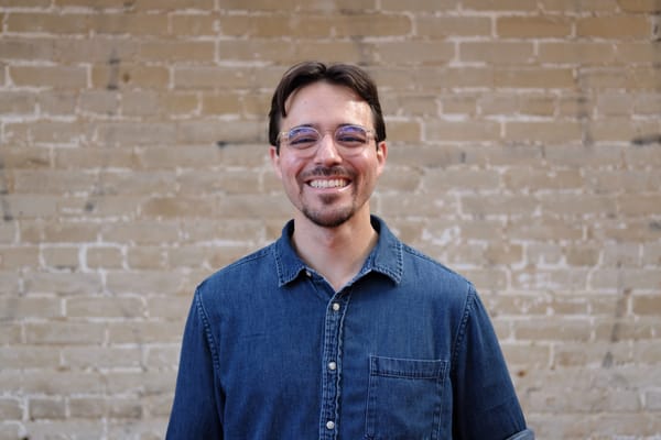 Photo showing Eric from the shoulders up, standing in front of a brick wall.