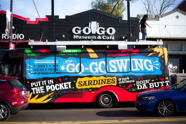 A big, multicolored bus that reads Go-Go Swing stands in front of the go-go museum and cafe. 