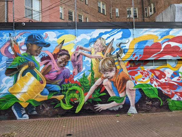 A mural painted in D.C., there are four children tending to the soil, with vibrant greens growing out of the earth.