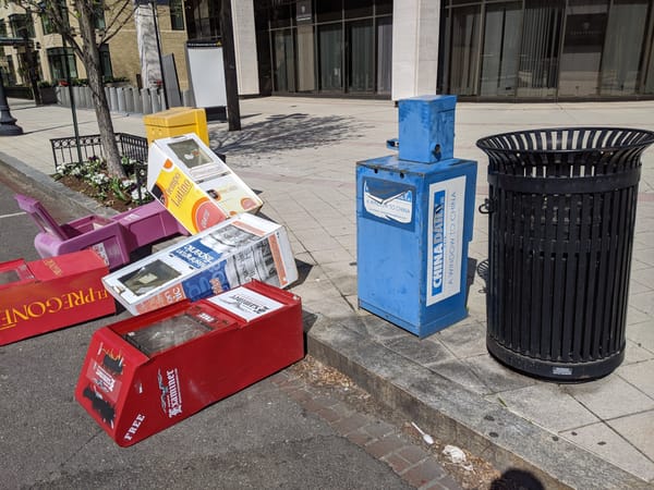 Colorful newspaper boxes in various states of knocked over along a sidewalk in D.C. 