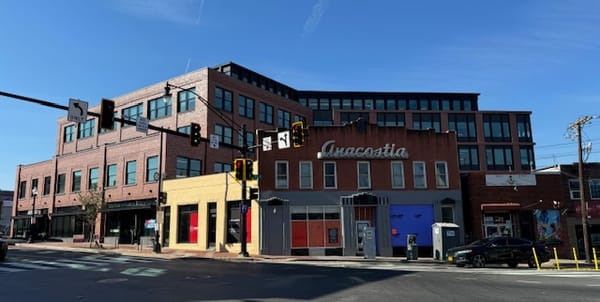 Photo of an older building that reads Anacostia, in front of a newer brick development. 