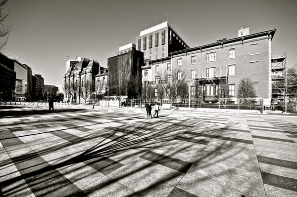 A black and white photograph of two people walking down D.C.'s Pennsylvania Avenue.