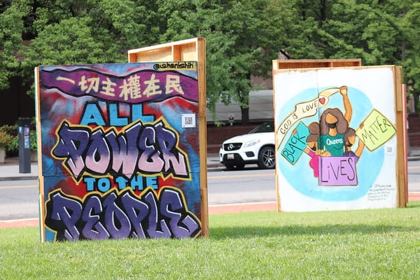 Two murals on a lawn. One says: "All power to the people." The other says: "God is Love and Black Lives Matter."