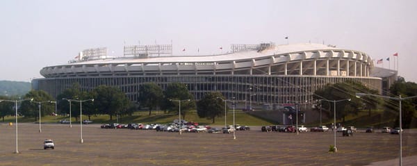 Outside shot of a large stadium with a few cars in a parking lo