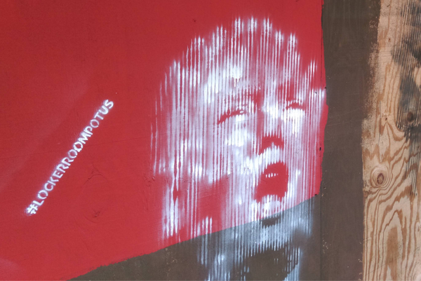 Trumps face spray painted in white on a red wall with #LOCKER ROOM POTUS next to it.