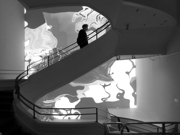 A black and white image of a person walking up the staircase at the Phillips Collection. 