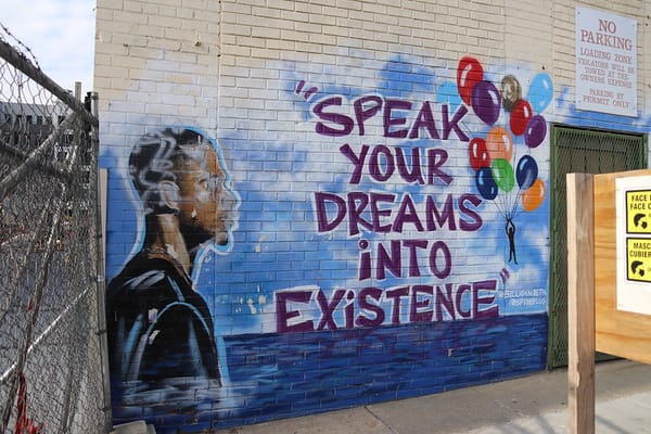 Mural of Black male looking toward text that says "Speak your dreams into existence." 