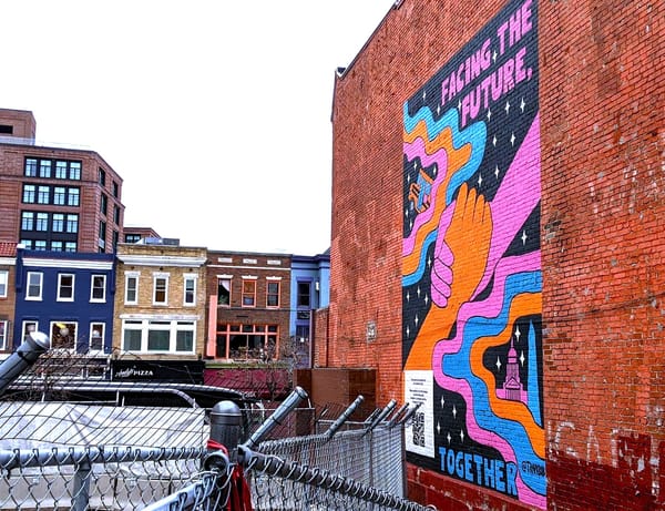 Photo of row houses and a mural on a brick wall that says 'Facing the future together'