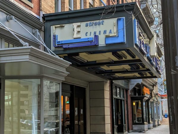 A sign reads E Street Cinema over a sidewalk. 