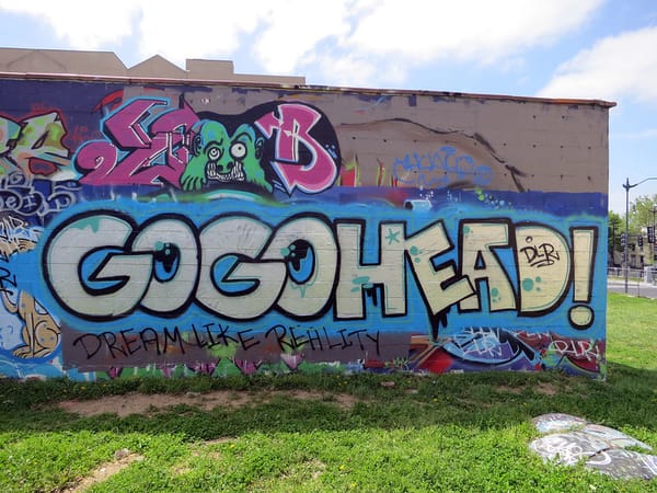 Colorful mur that says GOGOHEAD! with green creature in the background.