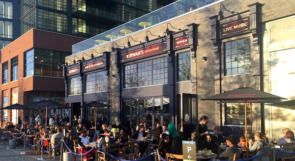 People are seated at tables outside of a restaurant called Kirwan's on the Wharf.