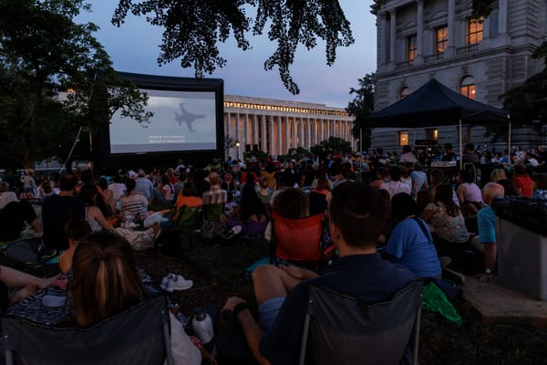A gathering at dusk before a screen.