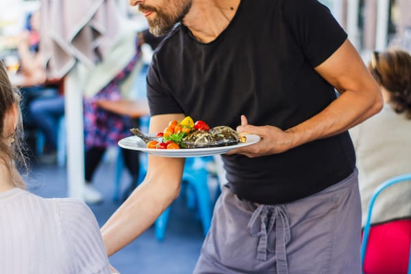 Restaurant brings colorful plate of food to guest on outdoor patio.